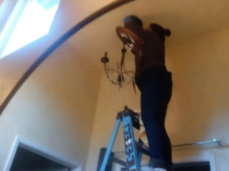 Electrician installing a chandelier in a San Clemente residence